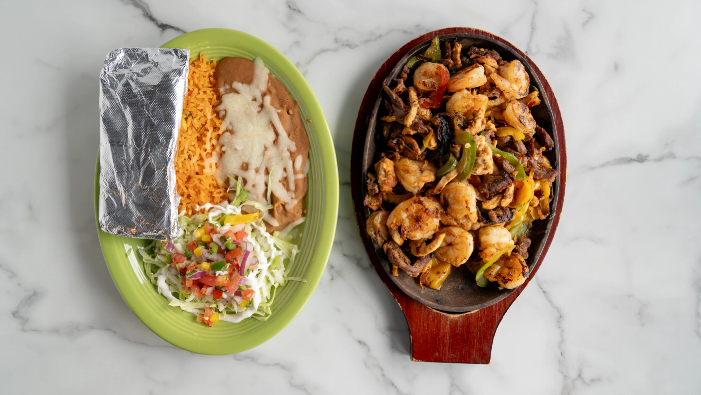 Tender grilled steak, chicken, and shrimp served sizzling with sautéed bell peppers, onions, and tomatoes. Comes with rice, beans, lettuce, sour cream, shredded cheese, pico de gallo, an extra tomato slice, and your choice of three flour or corn tortillas